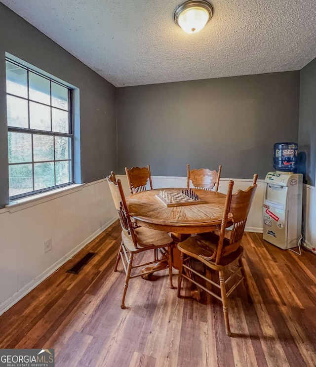 dining space featuring dark wood-type flooring and a textured ceiling