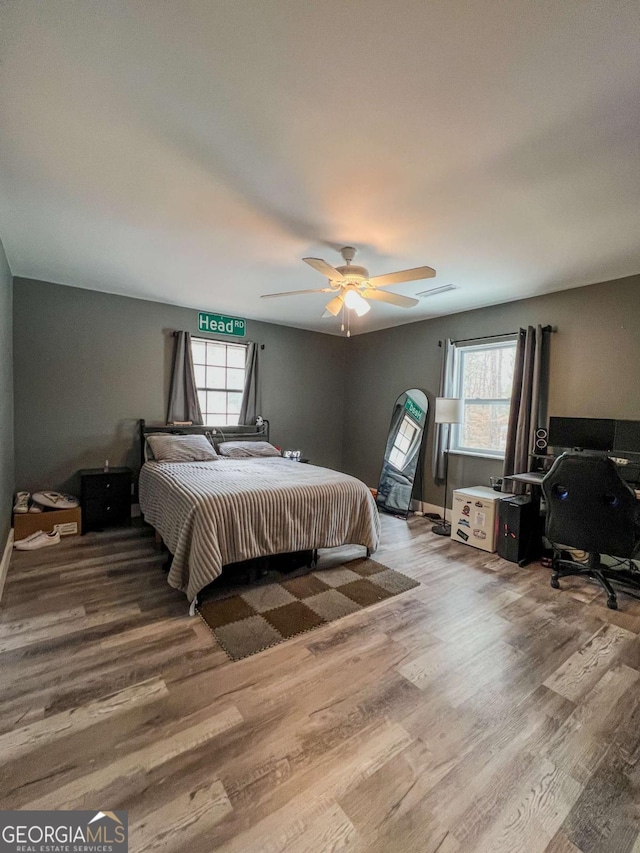 bedroom with hardwood / wood-style flooring, multiple windows, and ceiling fan