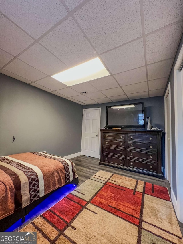 bedroom with a drop ceiling and dark hardwood / wood-style floors