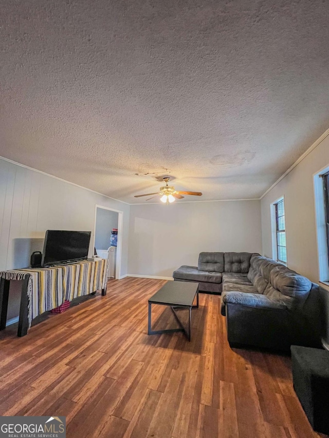 living room featuring hardwood / wood-style flooring, ceiling fan, crown molding, and a textured ceiling