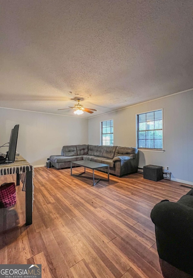 living room with ceiling fan, hardwood / wood-style floors, a textured ceiling, and a baseboard heating unit