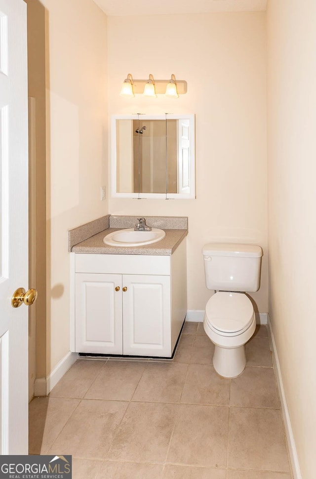 bathroom with toilet, vanity, and tile patterned floors