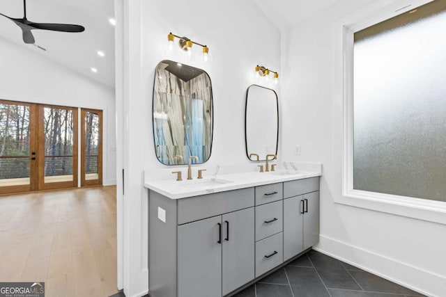 bathroom with ceiling fan, a healthy amount of sunlight, vaulted ceiling, and vanity