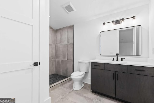 bathroom with toilet, vanity, and a tile shower