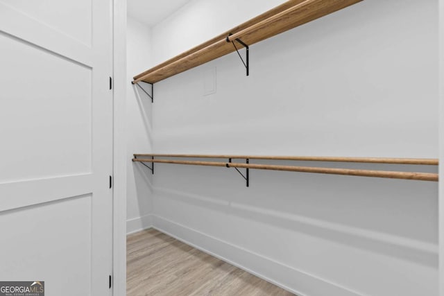 walk in closet with light hardwood / wood-style flooring