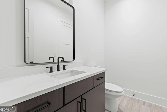 bathroom with hardwood / wood-style floors, toilet, and vanity