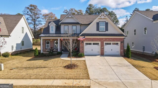 craftsman-style home with covered porch, a front yard, and a garage