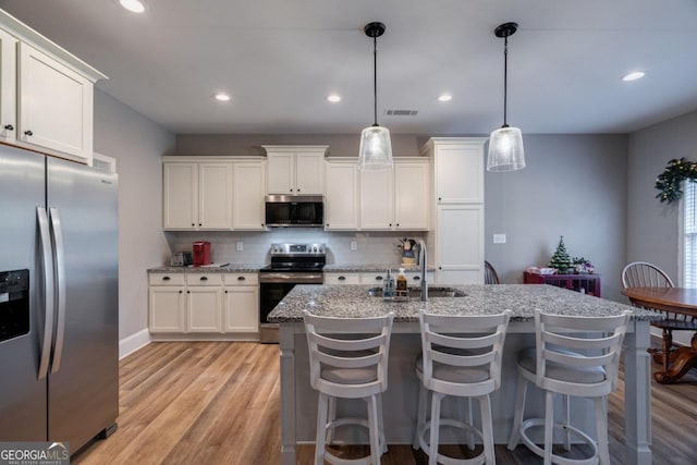 kitchen with pendant lighting, appliances with stainless steel finishes, and white cabinets