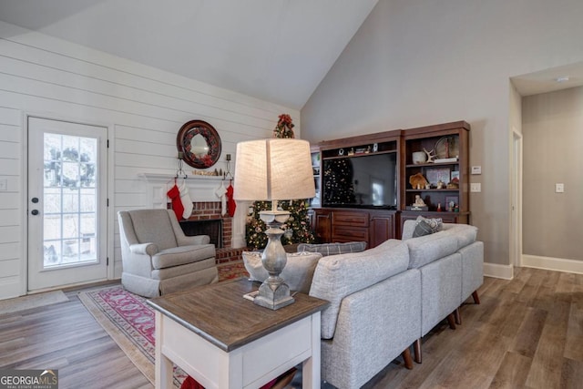 living room featuring hardwood / wood-style flooring, high vaulted ceiling, and a fireplace