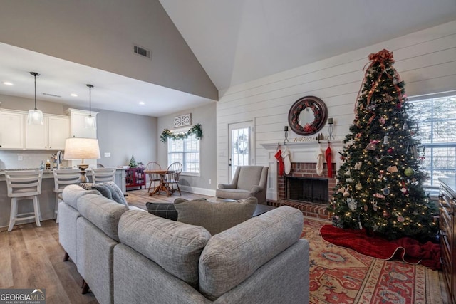 living room featuring a fireplace, high vaulted ceiling, and light hardwood / wood-style flooring