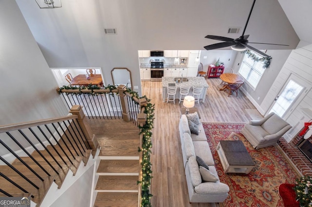 living room with hardwood / wood-style flooring, ceiling fan, and a high ceiling