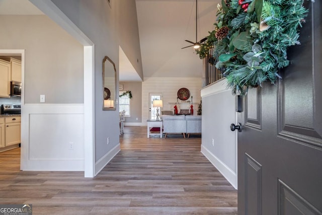 entrance foyer featuring a towering ceiling, ceiling fan, and light hardwood / wood-style flooring