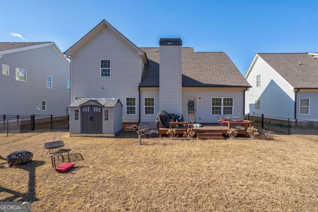 rear view of house featuring a wooden deck, a fire pit, and a shed