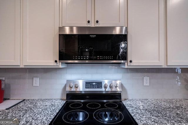 kitchen featuring stainless steel electric stove, light stone countertops, and white cabinets