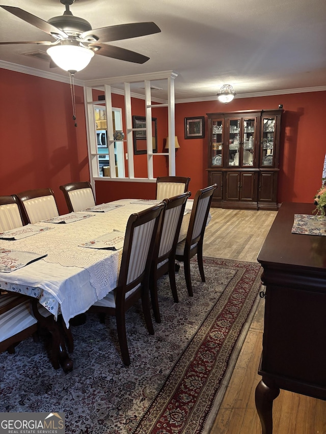 dining space featuring ornamental molding, light wood-type flooring, and ceiling fan