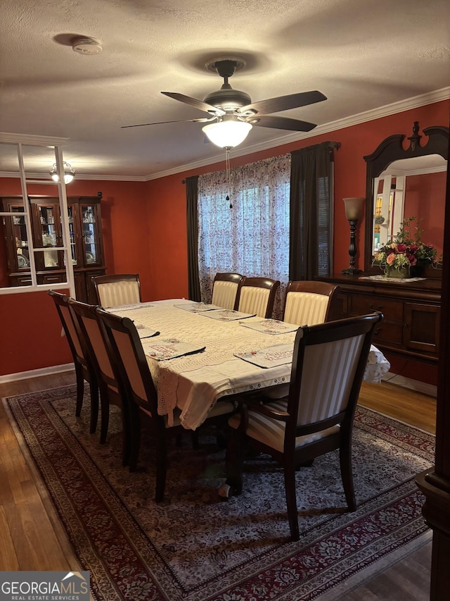 dining area featuring a textured ceiling, a ceiling fan, dark wood finished floors, and crown molding