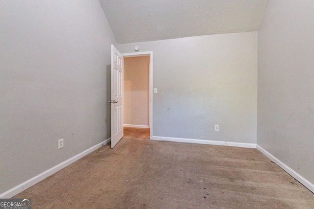 spare room with a textured ceiling, carpet, and lofted ceiling