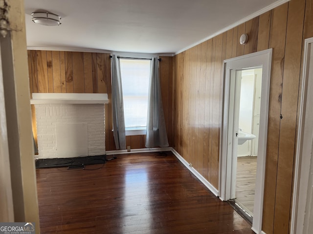 unfurnished living room featuring wooden walls, a fireplace, dark hardwood / wood-style floors, and ornamental molding