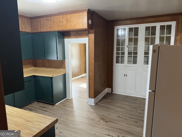 kitchen featuring white fridge, light hardwood / wood-style floors, and wooden walls