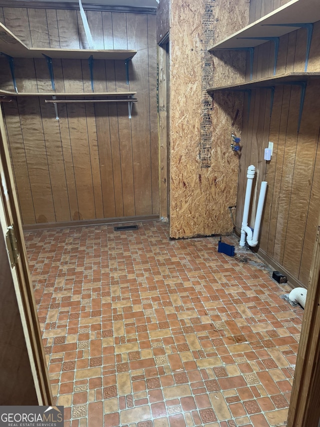 laundry room with wood walls