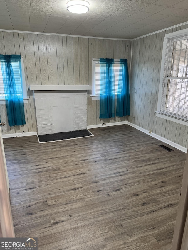 unfurnished living room with hardwood / wood-style floors, plenty of natural light, and wooden walls