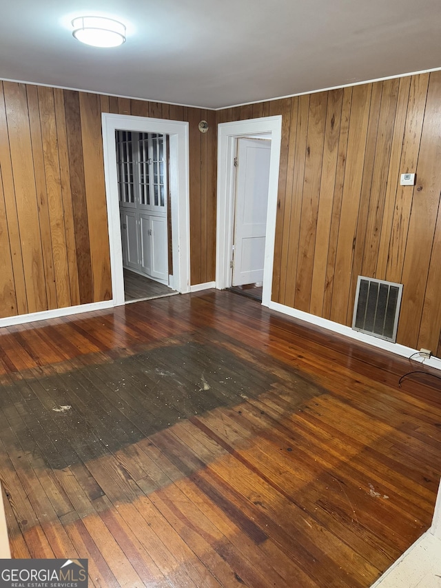 spare room featuring wooden walls and dark wood-type flooring