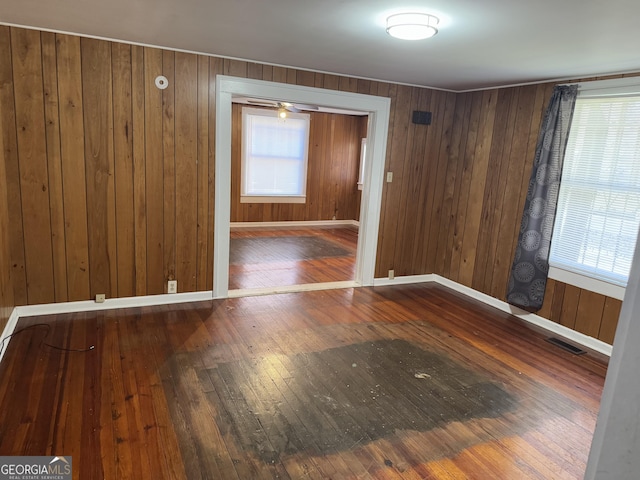 unfurnished room featuring dark hardwood / wood-style floors, plenty of natural light, and wooden walls