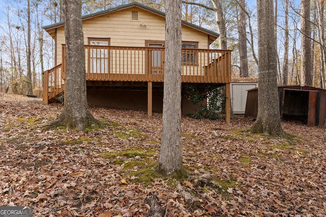 back of house with a deck and a storage shed