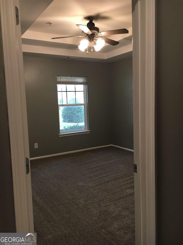 carpeted empty room with a tray ceiling and ceiling fan