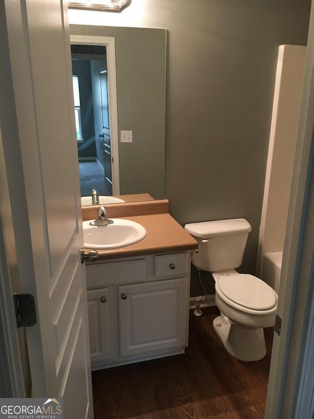 bathroom with a bathing tub, vanity, wood-type flooring, and toilet