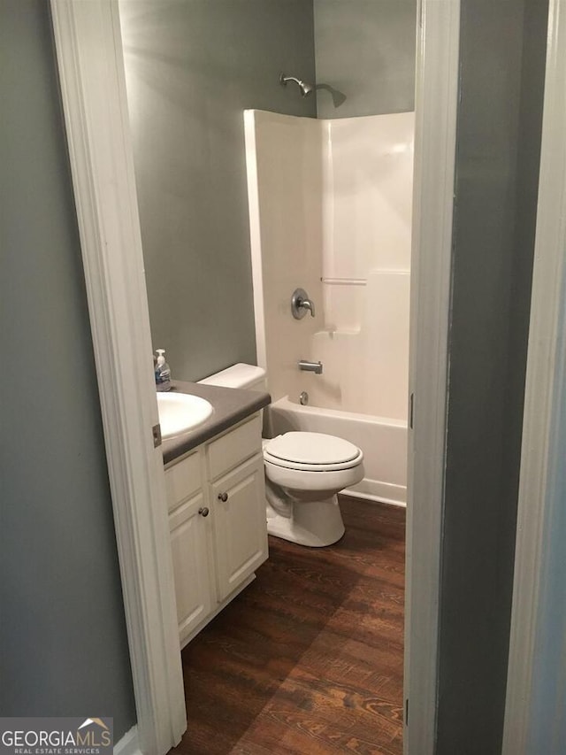 full bathroom with shower / washtub combination, vanity, wood-type flooring, and toilet