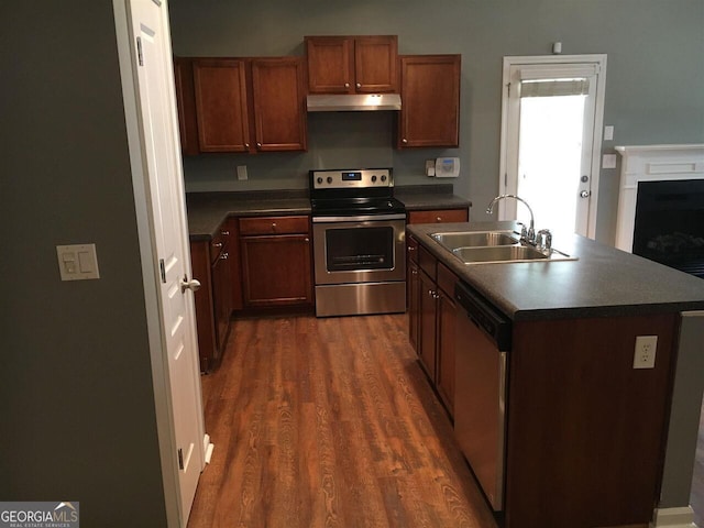 kitchen featuring stainless steel appliances, a kitchen island with sink, dark wood-type flooring, and sink