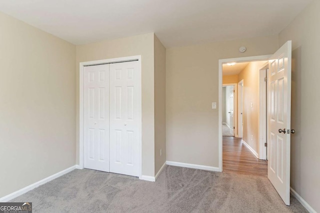 unfurnished bedroom featuring light colored carpet and a closet