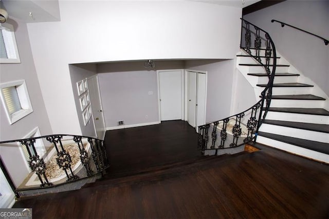 stairs with hardwood / wood-style floors and a towering ceiling