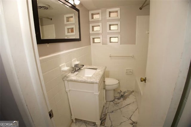 bathroom featuring vanity, toilet, and tile walls