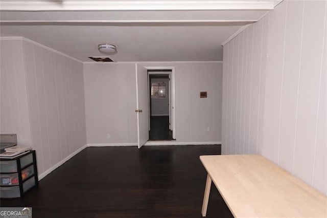 interior space featuring wood walls, ornamental molding, and dark wood-type flooring