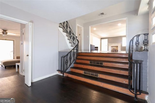 stairs with a fireplace, hardwood / wood-style flooring, and plenty of natural light