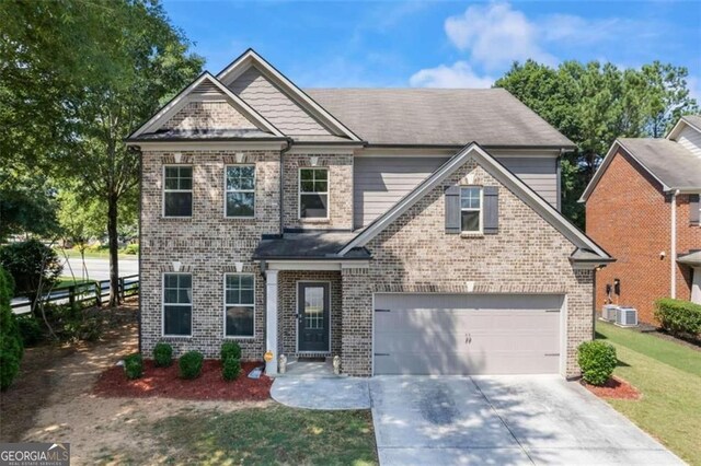 view of front of home with central AC unit, a garage, and a front lawn