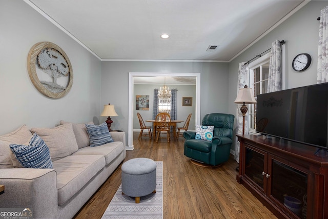 living room featuring a wealth of natural light, crown molding, wood-type flooring, and an inviting chandelier