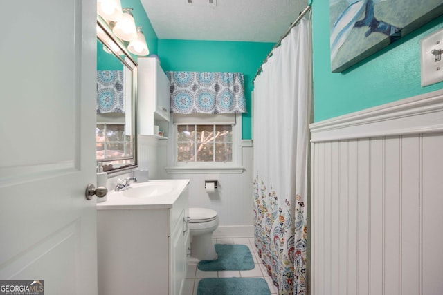 bathroom featuring toilet, vanity, tile patterned floors, and walk in shower