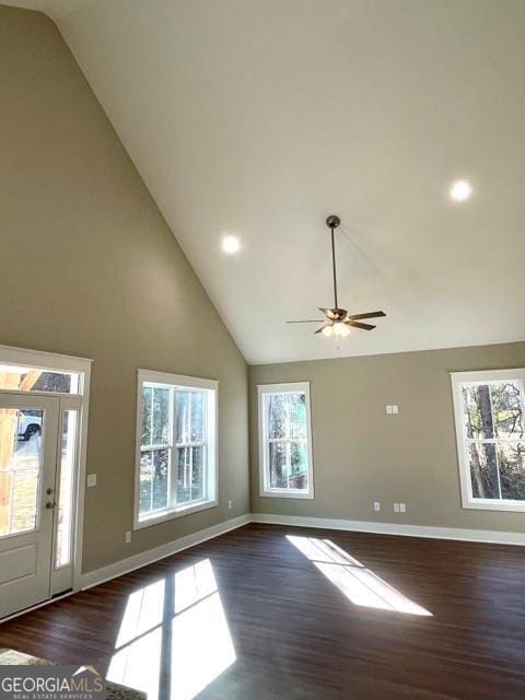 unfurnished living room with a wealth of natural light, high vaulted ceiling, and dark hardwood / wood-style floors