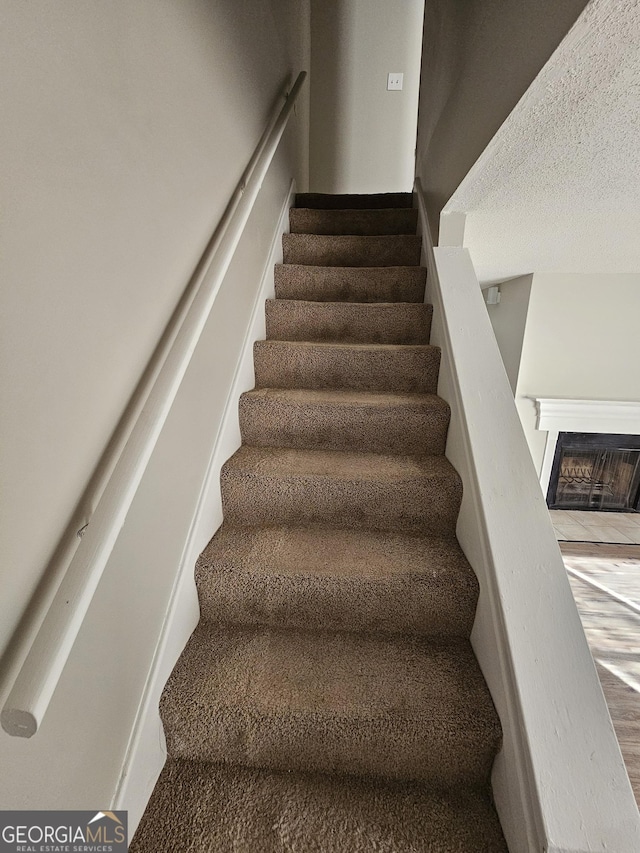 stairway featuring a fireplace and a textured ceiling