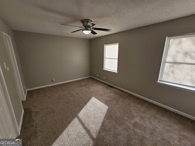 carpeted empty room featuring visible vents, baseboards, a textured ceiling, and ceiling fan