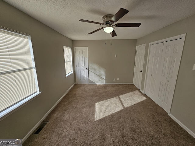 unfurnished bedroom with visible vents, baseboards, carpet, and a textured ceiling