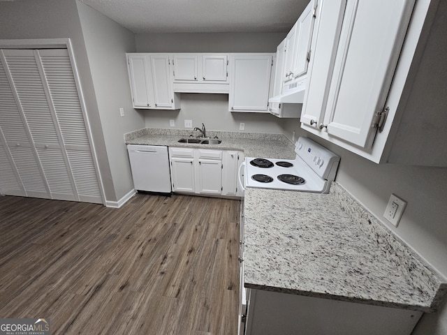 kitchen with under cabinet range hood, a sink, dark wood finished floors, white cabinetry, and white appliances