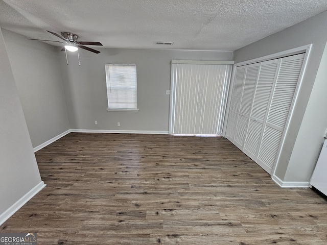 unfurnished bedroom with visible vents, a textured ceiling, baseboards, and wood finished floors