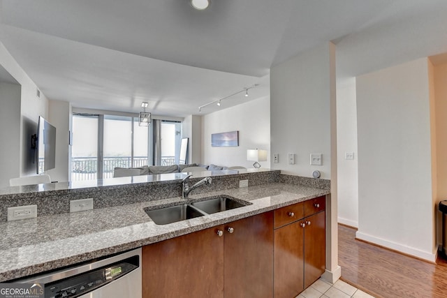 kitchen featuring light stone countertops, sink, light tile patterned flooring, and stainless steel dishwasher