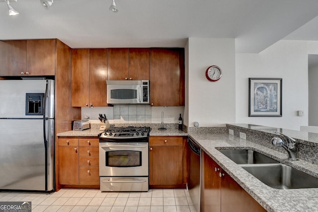 kitchen with light tile patterned floors, stainless steel appliances, light stone counters, and sink