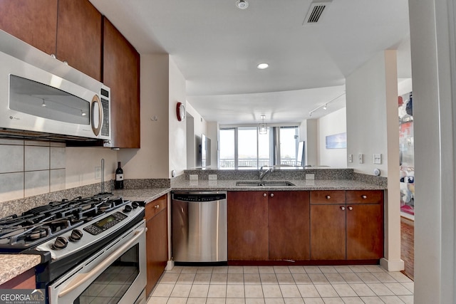 kitchen featuring sink, rail lighting, light tile patterned floors, appliances with stainless steel finishes, and stone countertops