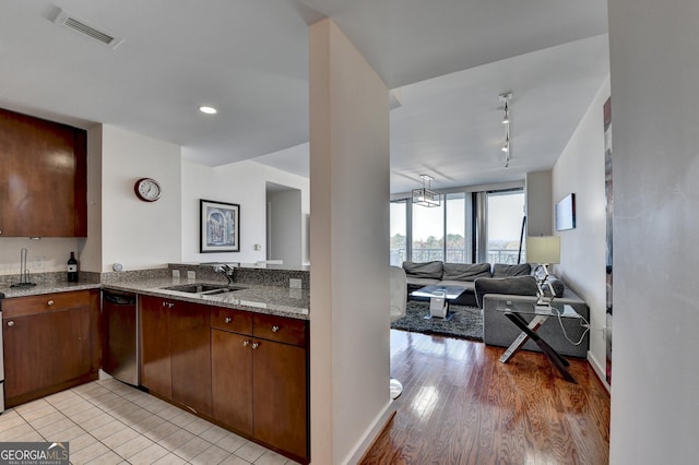 kitchen with dishwasher, sink, light stone counters, track lighting, and light wood-type flooring